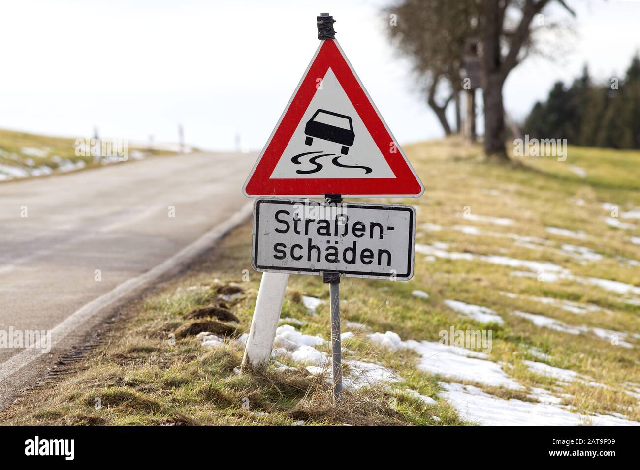 street sign in germany warning Slippery road (water, ice, snow, oil or dirt) - text translation 'damaged street' Stock Photo