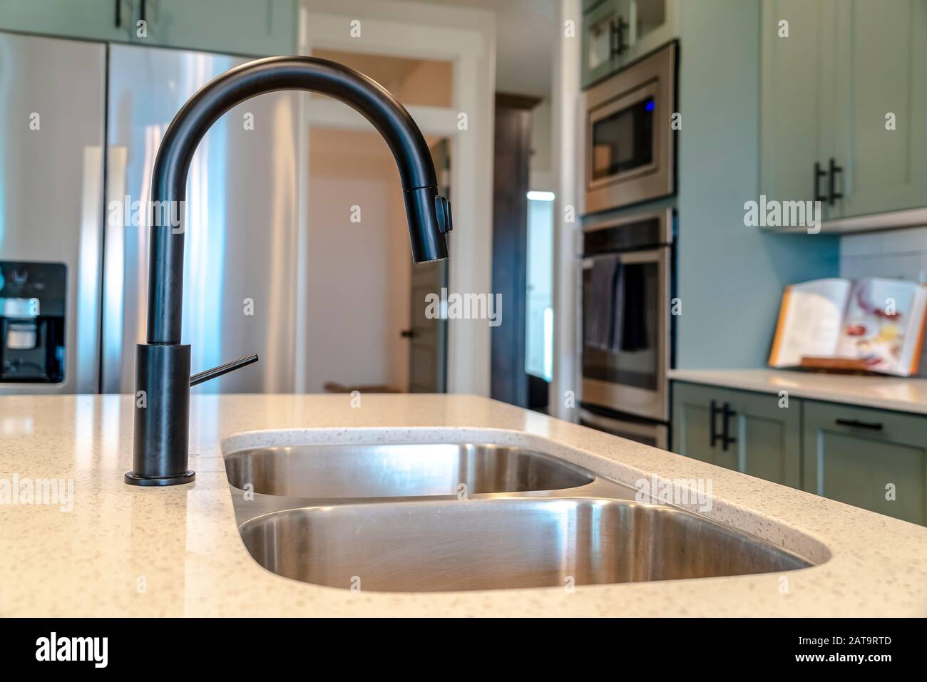 Kitchen island sink with double bowl and black faucet against kitchen