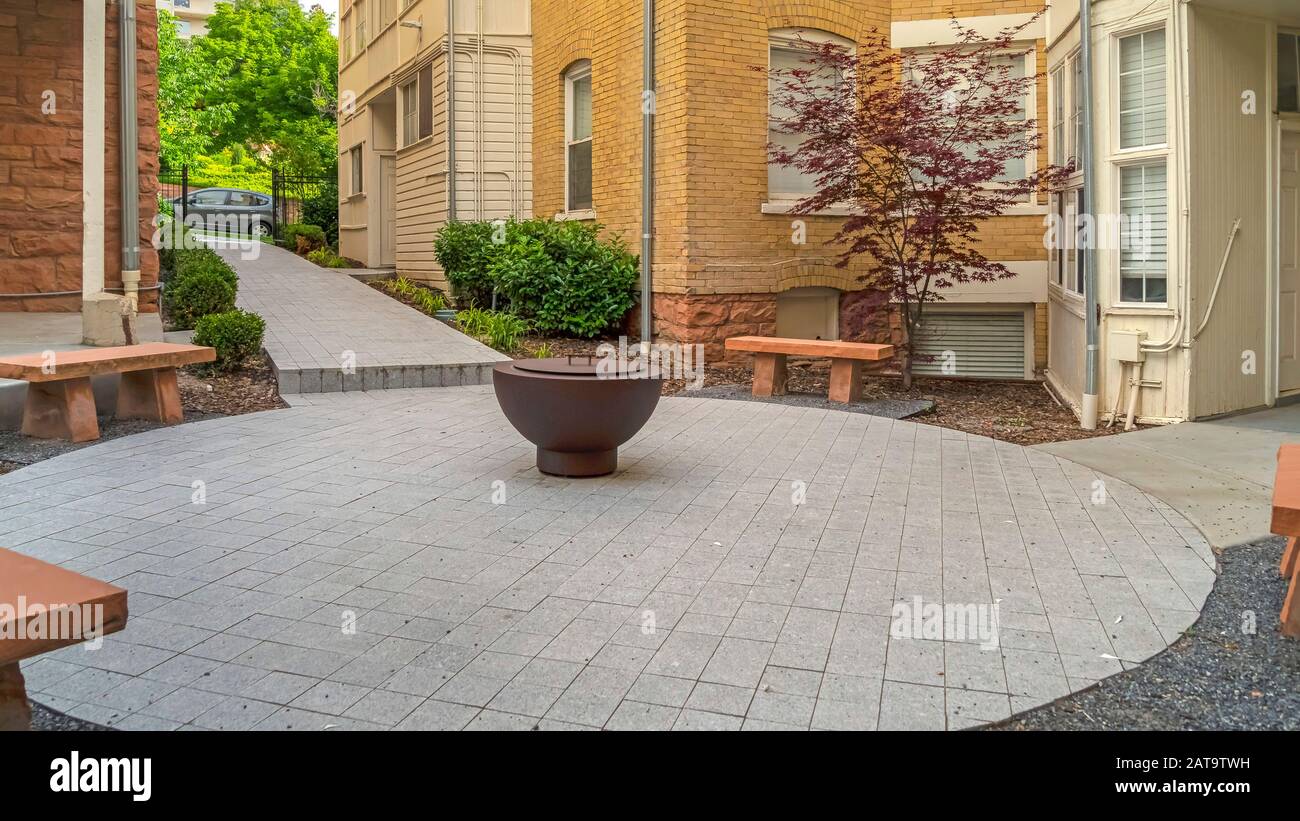 Panorama Fire pit on circular patio outside building with white and ...
