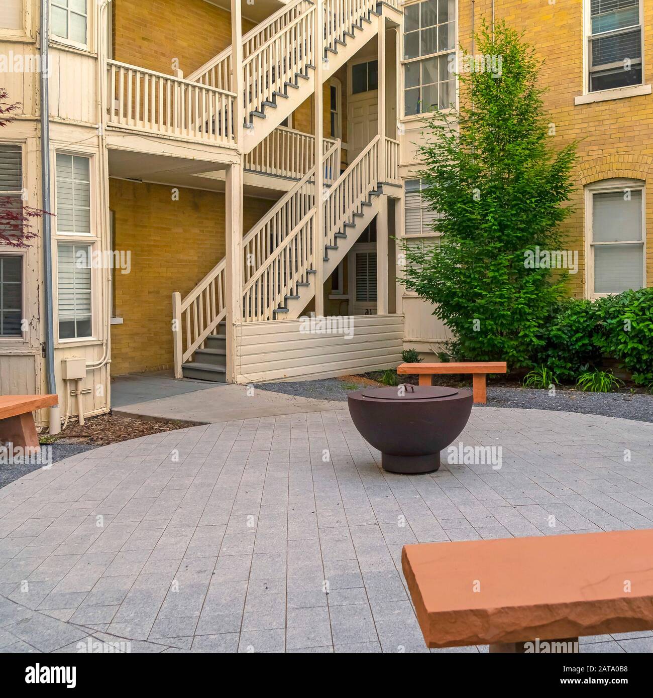 Square Fire pit on circular pavement with stone benches against