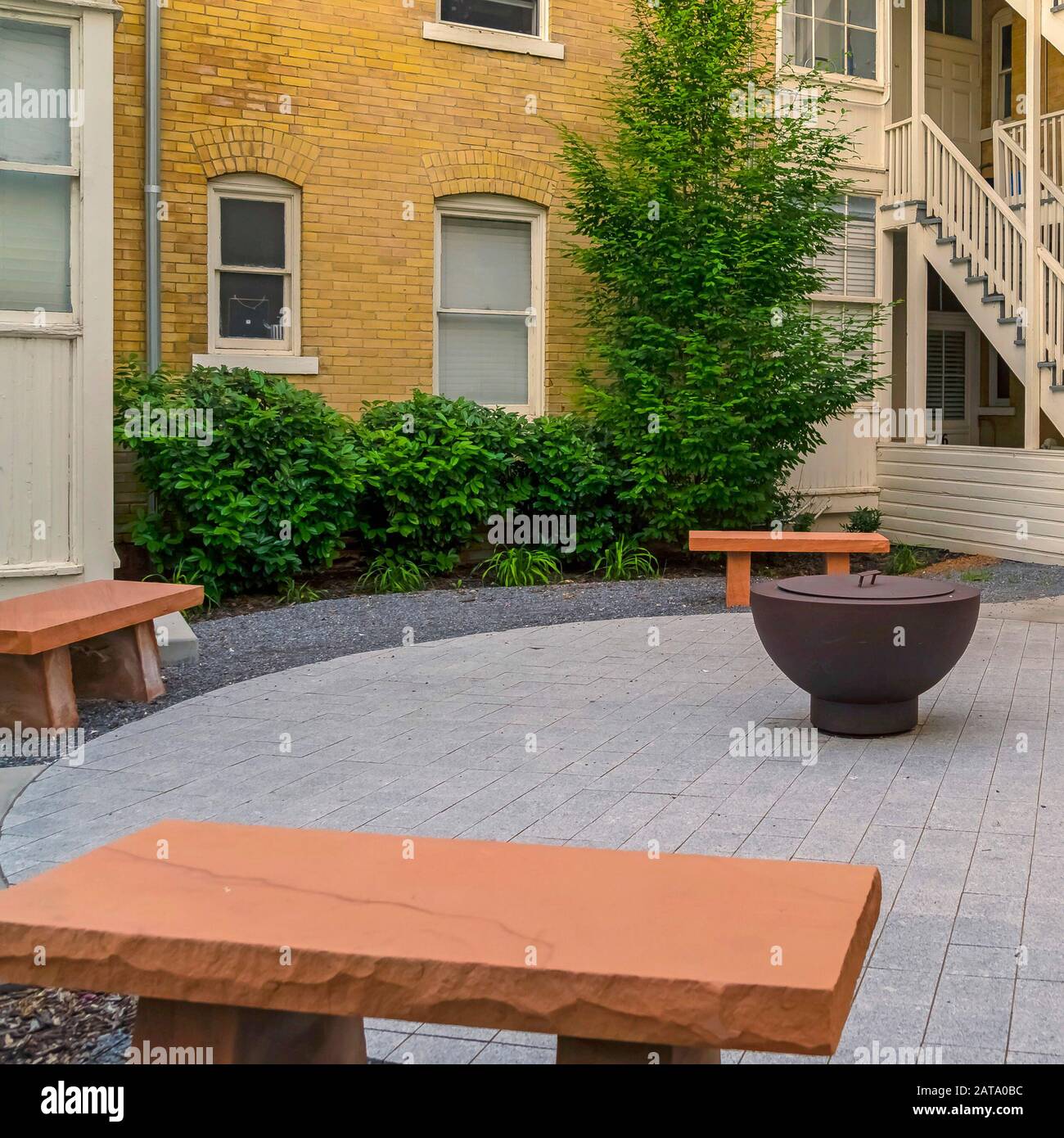 Square Frame Fire Pit On Circular Pavement With Stone Benches