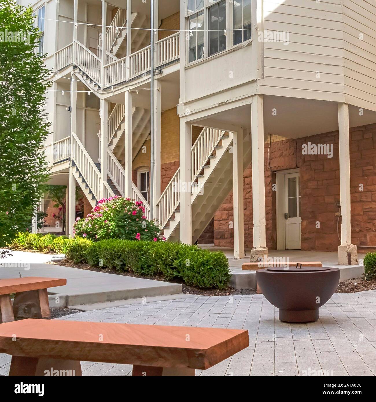 Square Frame Fire Pit And Stone Benches Against Building With