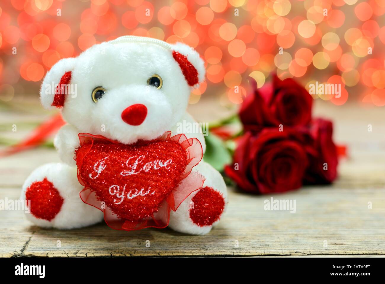 Valentines day concept. White plush toy bear and red roses on an old ...