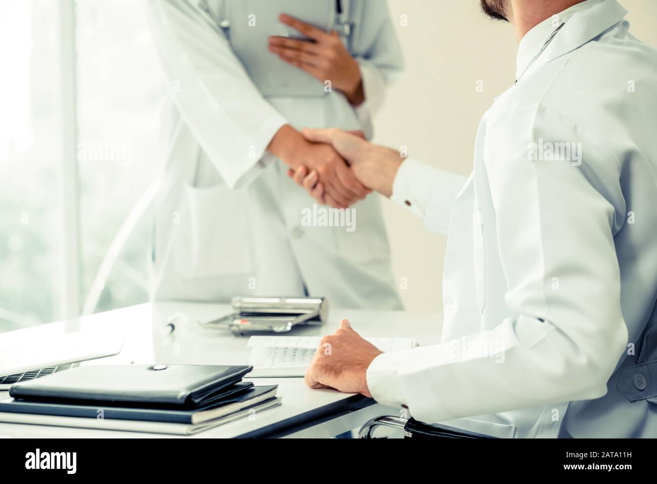 Doctor at the hospital giving handshake to another doctor showing