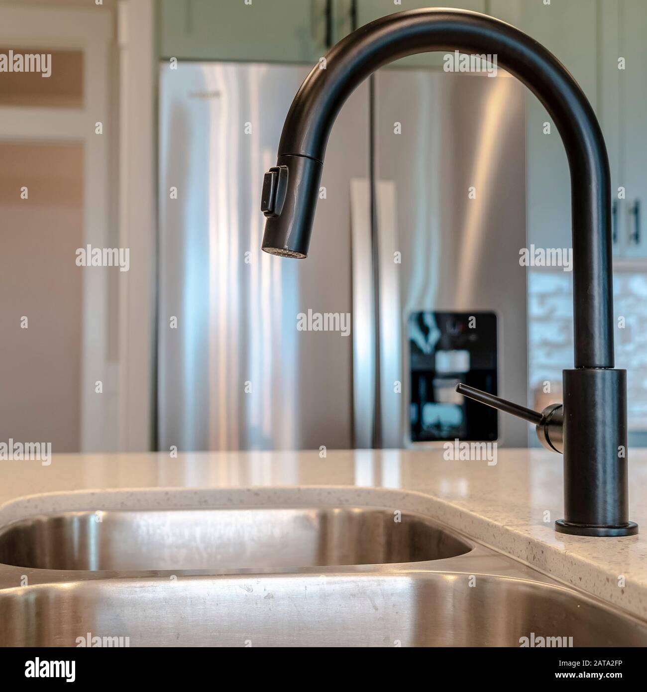 Square frame Double basin undermount kitchen sink with black faucet against refrigerator Stock