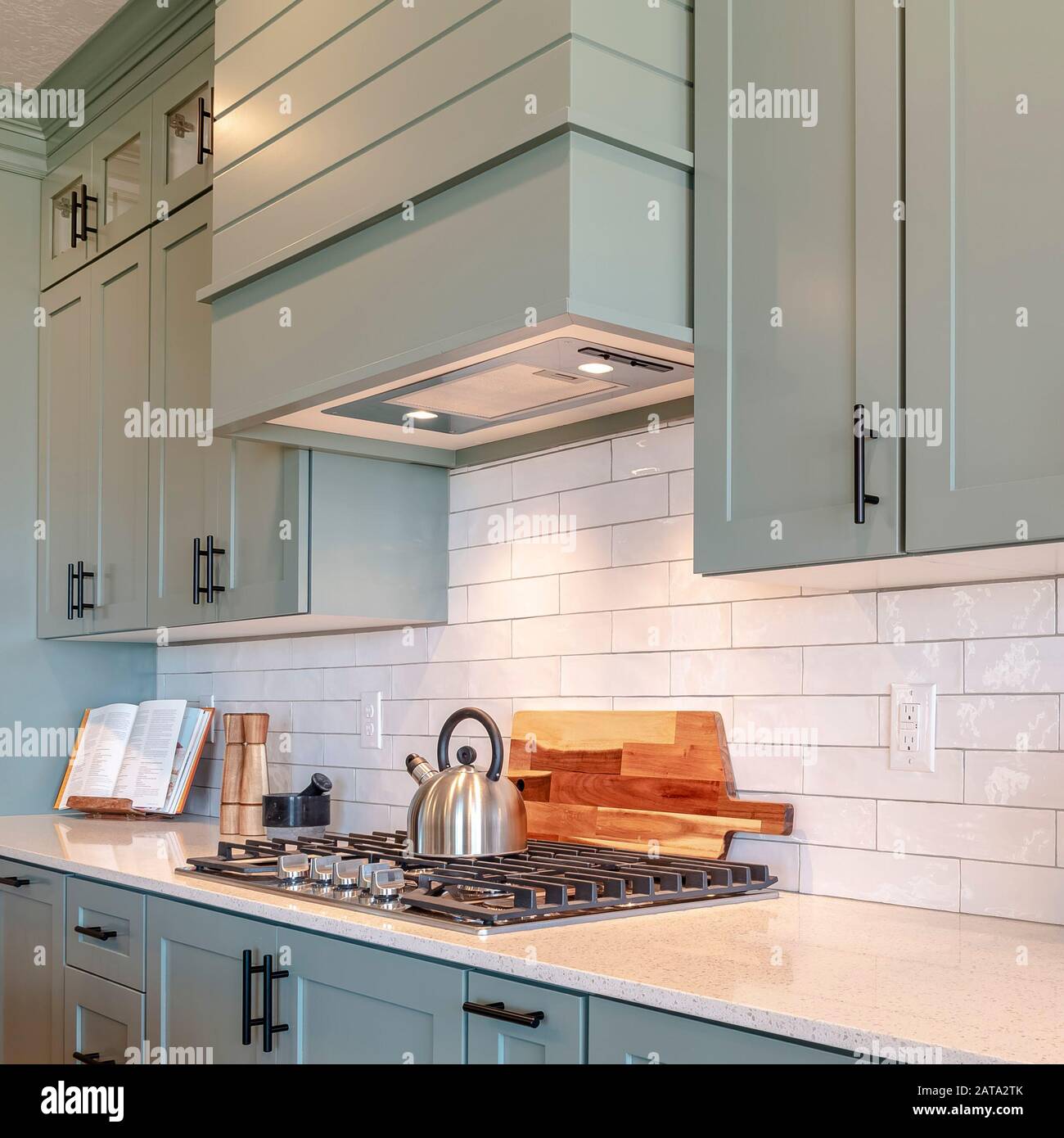 Square Kitchen interior with cooktop on white counter top under hanging