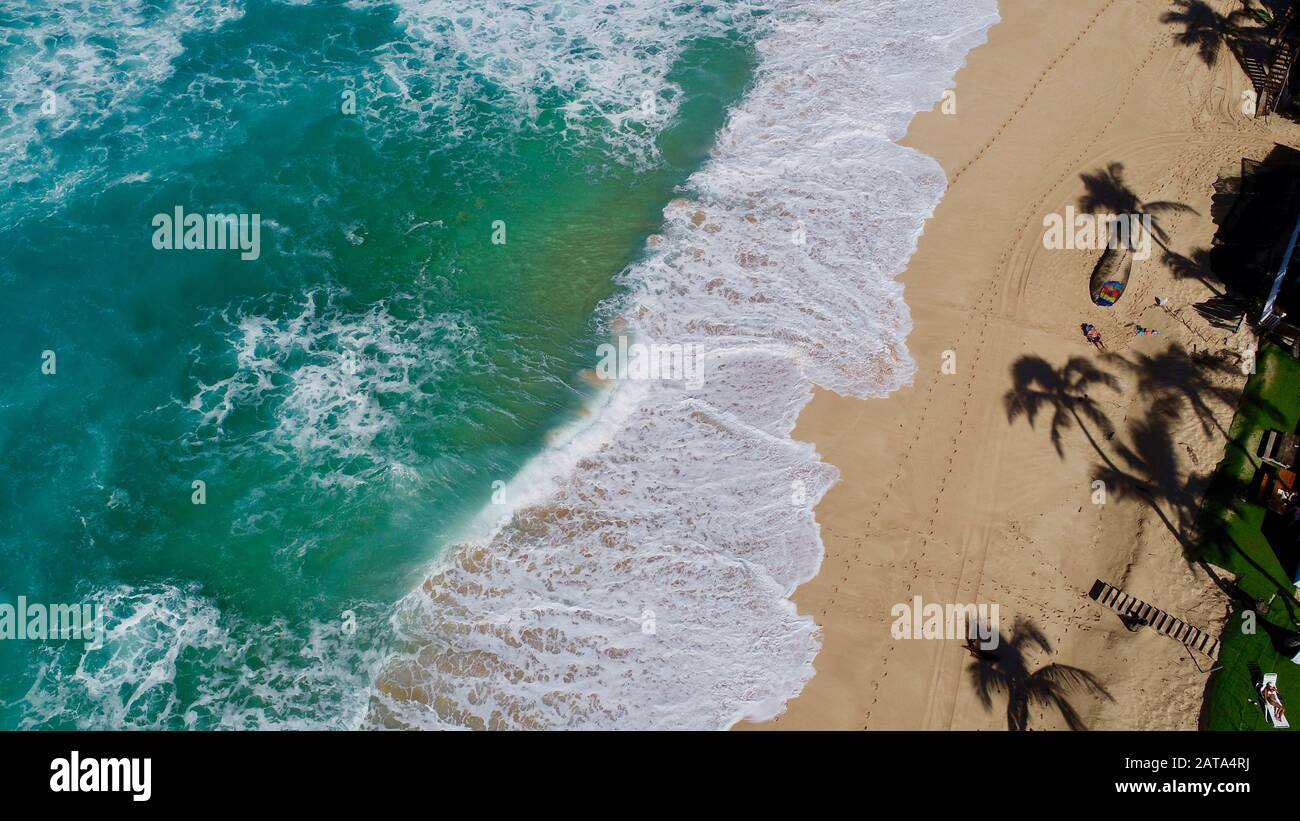 Aerial view of bright blue water and surf with waves crashing at Bonzai