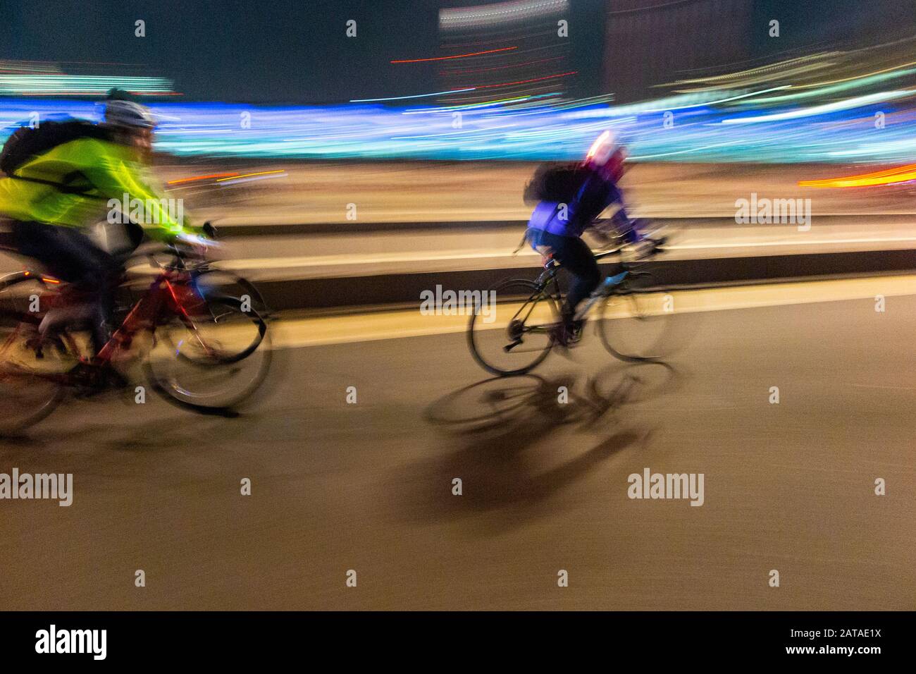 A cyclist leaves work and cycles fast at night to go home Stock Photo
