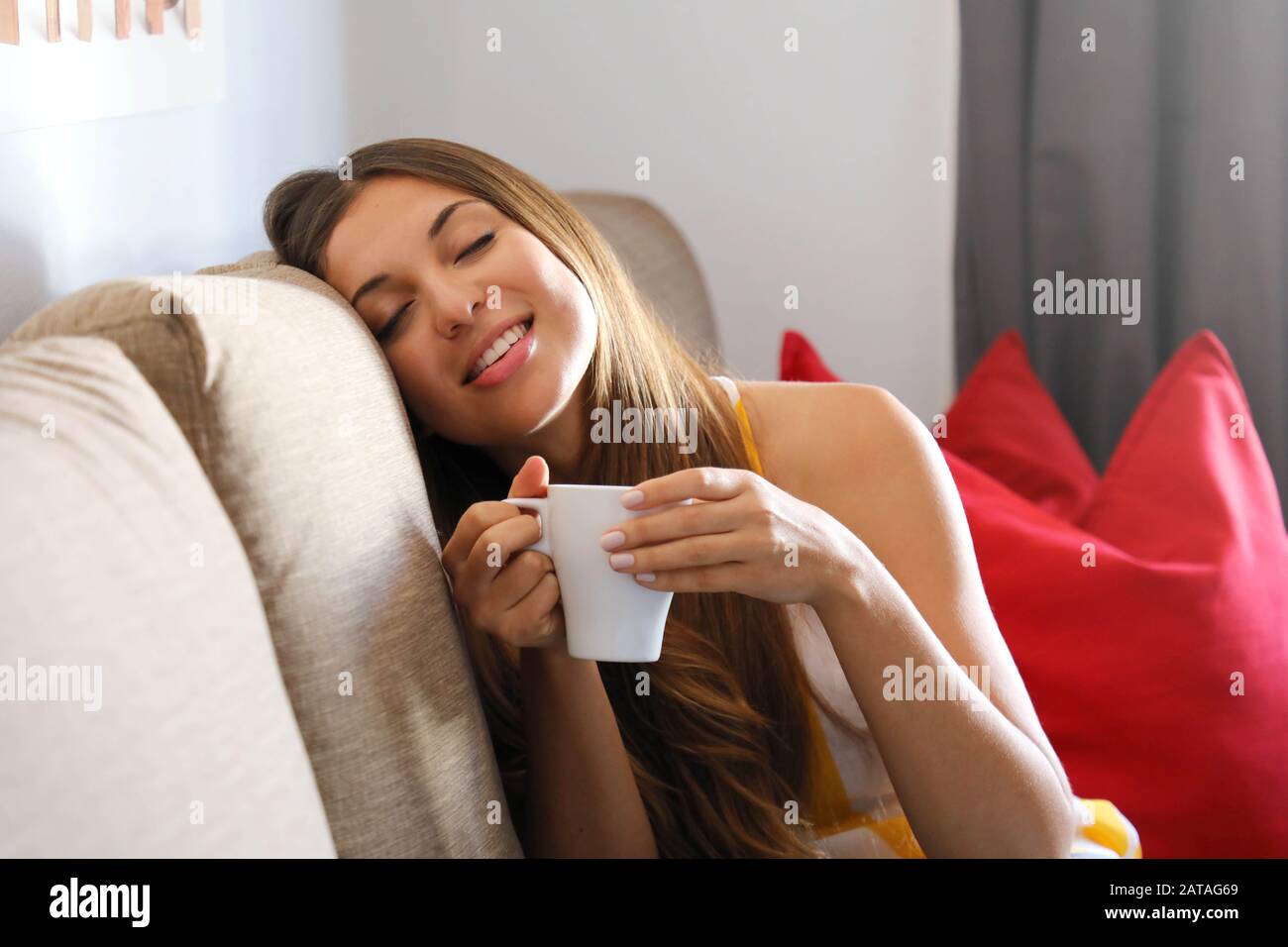 Relaxd woman enjoying a cup of tea sitting on a couch in the living ...