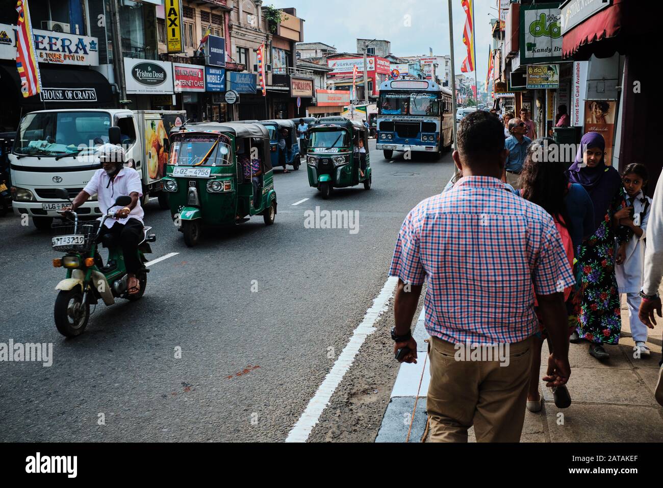 Street life in Sri Lanka, people walking on sidewalk, while busy traffic goes on. Bikes, Tuk tuk, bus... Stock Photo