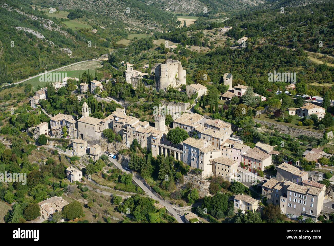PROVENCAL VILLAGE BUILT ON A HILL, CROWNED WITH A MEDIEVAL CASTLE IN RUINS (aerial view). Montbrun-les-Bains, Drome, France. Stock Photo