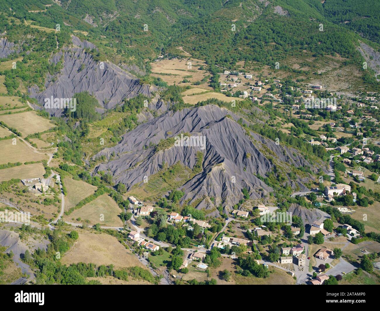 AERIAL VIEW. Village in a landscape of farmlands and badlands. La Robine-sur-Galabre, Alpes de Haute-Provence, France. Stock Photo