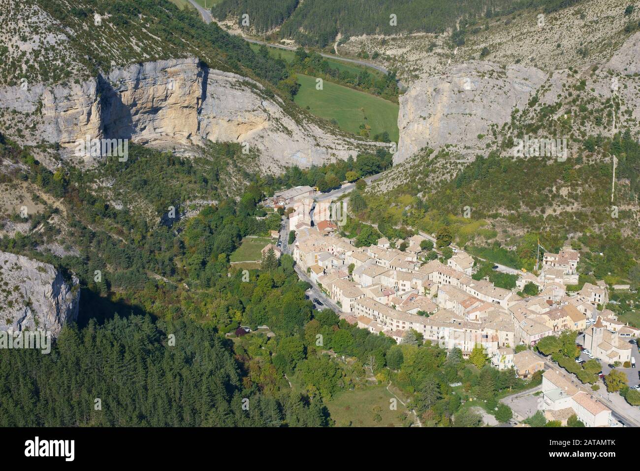 AERIAL VIEW. Picturesque village inside a valley with lofty cliffs. Orpierre, Hautes-Alpes, France. Stock Photo
