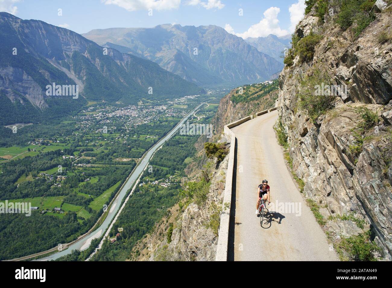 AERIAL VIEW from a 6m mast. Cyclist on a narrow road above a precipitous mountainside. Auris Road, above Le Bourg d'Oisans, France. Stock Photo