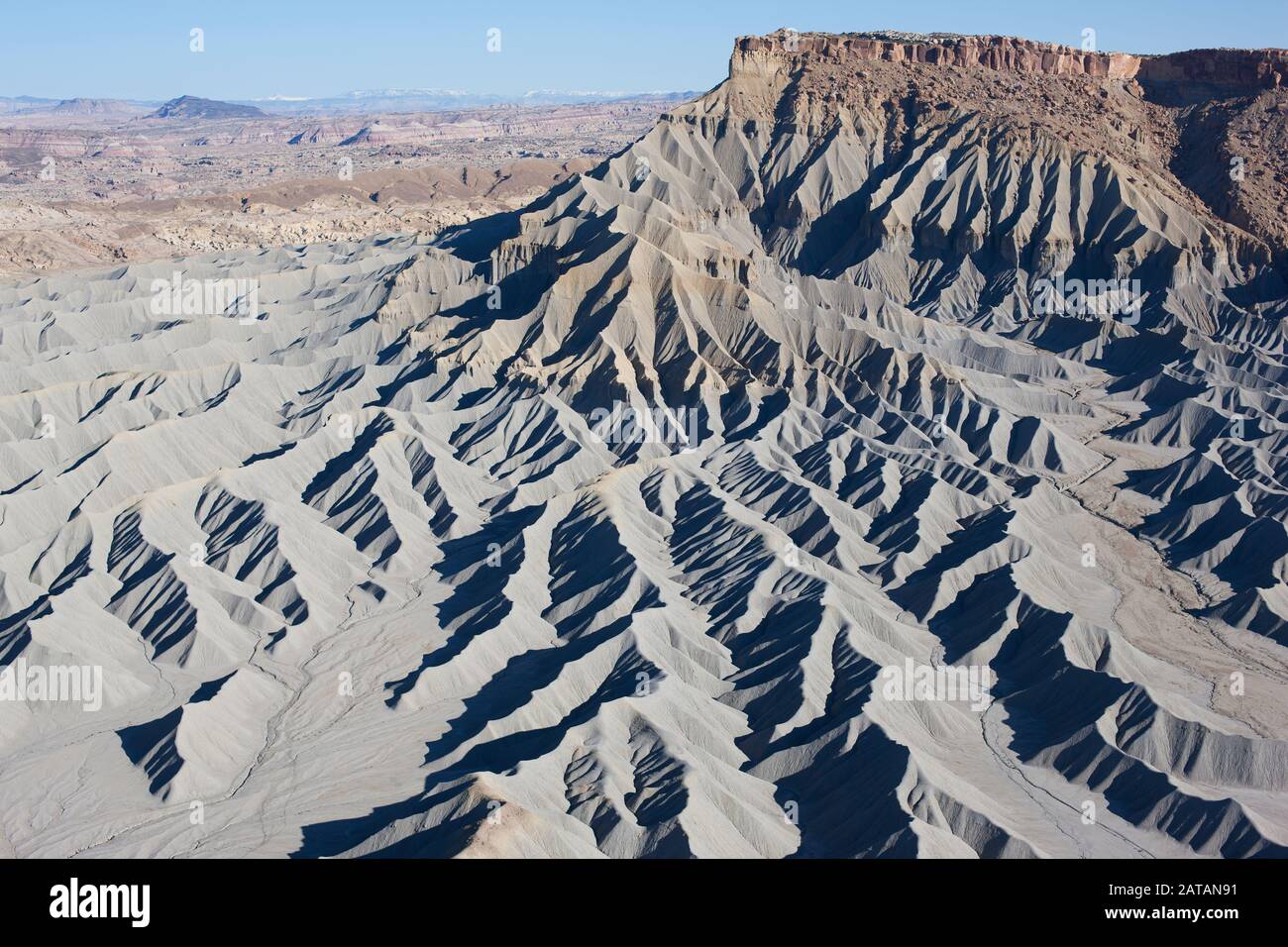 AERIAL VIEW. Landscape of grayish badlands at the foothills of a mesa. Caineville, Utah, USA. Stock Photo