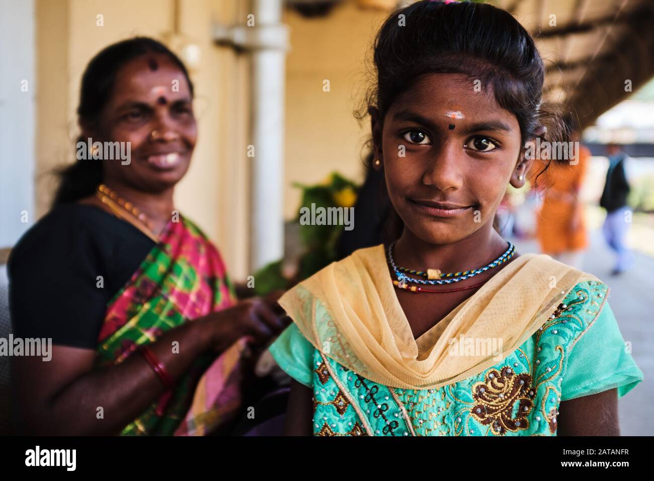 A young girl in traditional dress from Sri lanka poses at the train