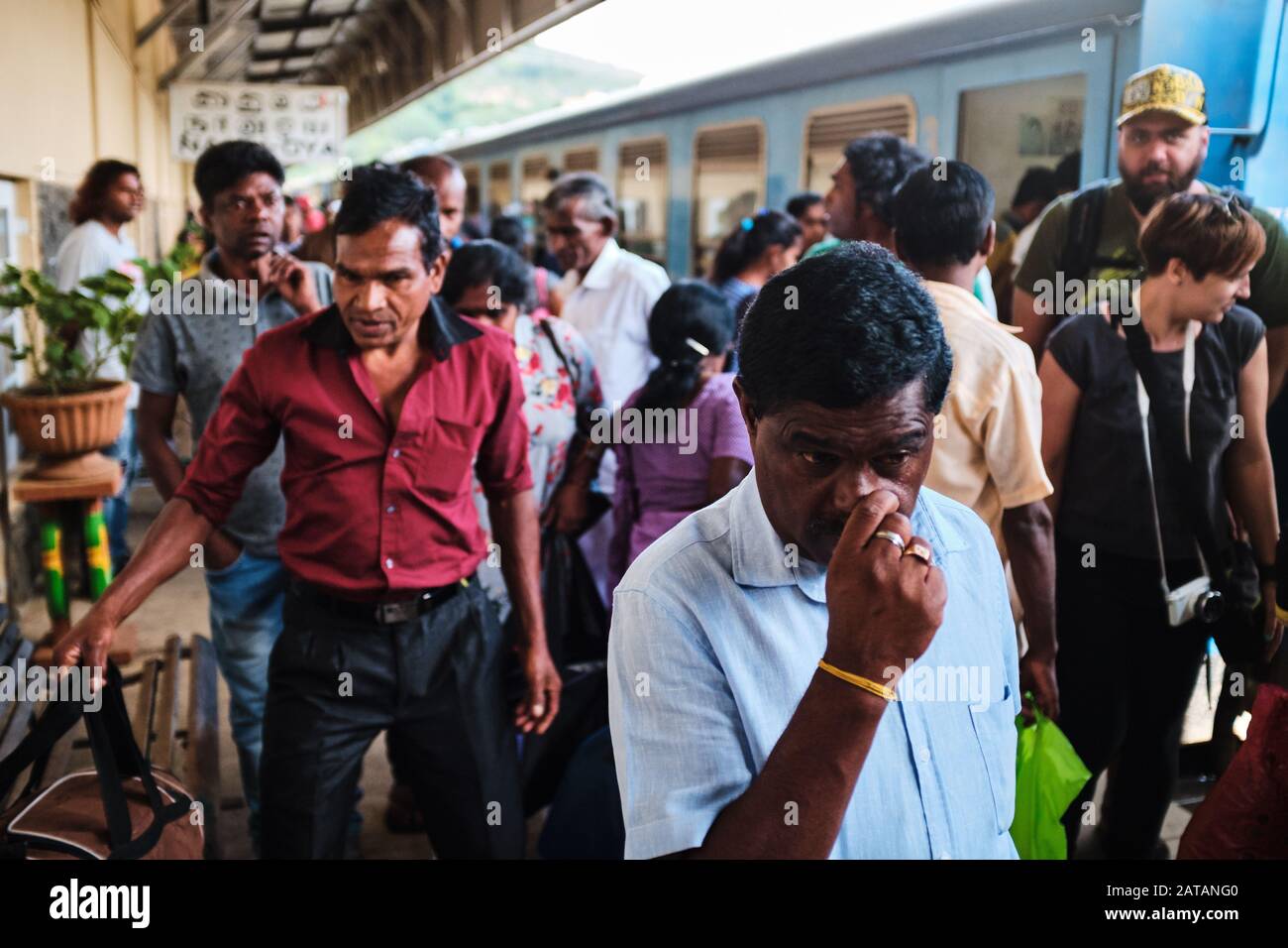 Group of local people exiting the train. One man is picking his nose. Sri Lanka. Stock Photo