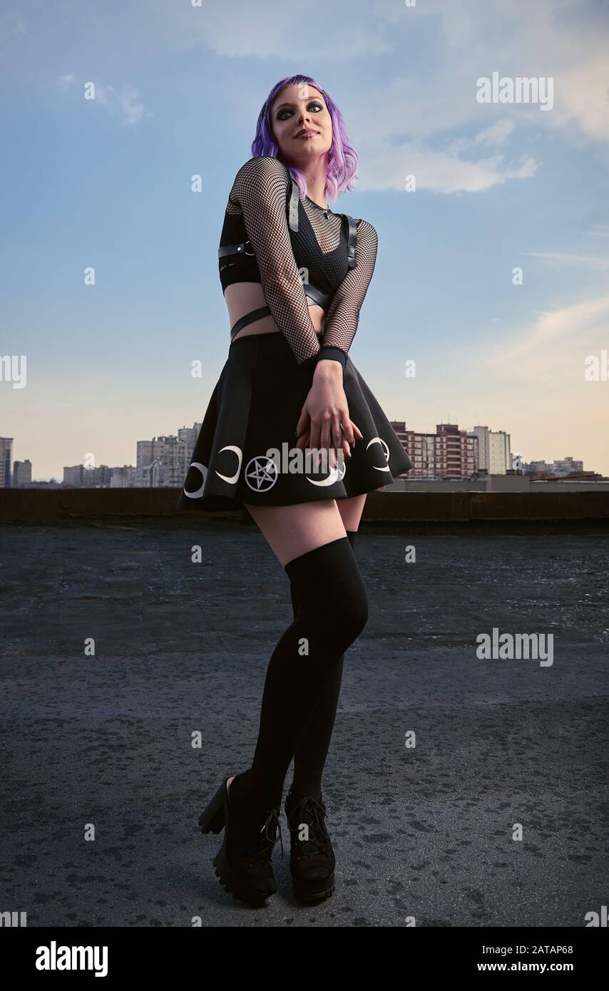 Portrait of cute smiling gothic girl on the roof at sunset time. Pastel goth  with violet (purple) hair in black clothes Stock Photo - Alamy