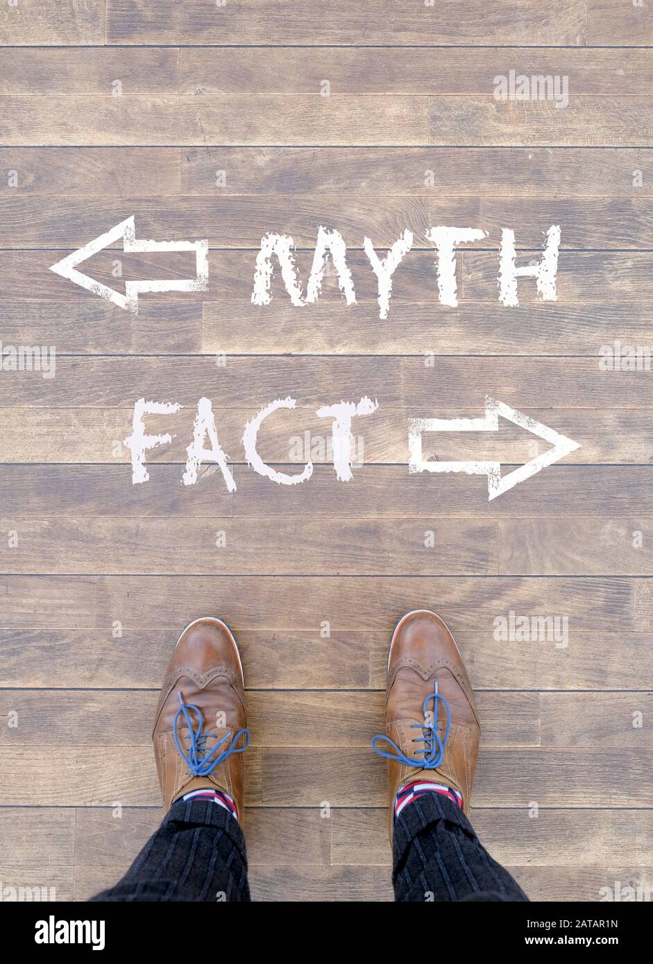Man standing in front of two arrows and the words 'Myth' and 'Fact' Stock Photo