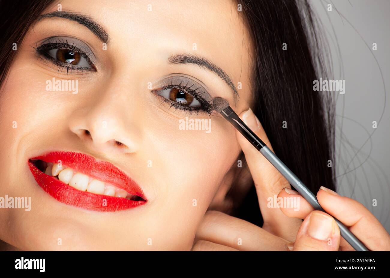 Young beautiful woman applying eyeliner on eyelid with pencil Stock