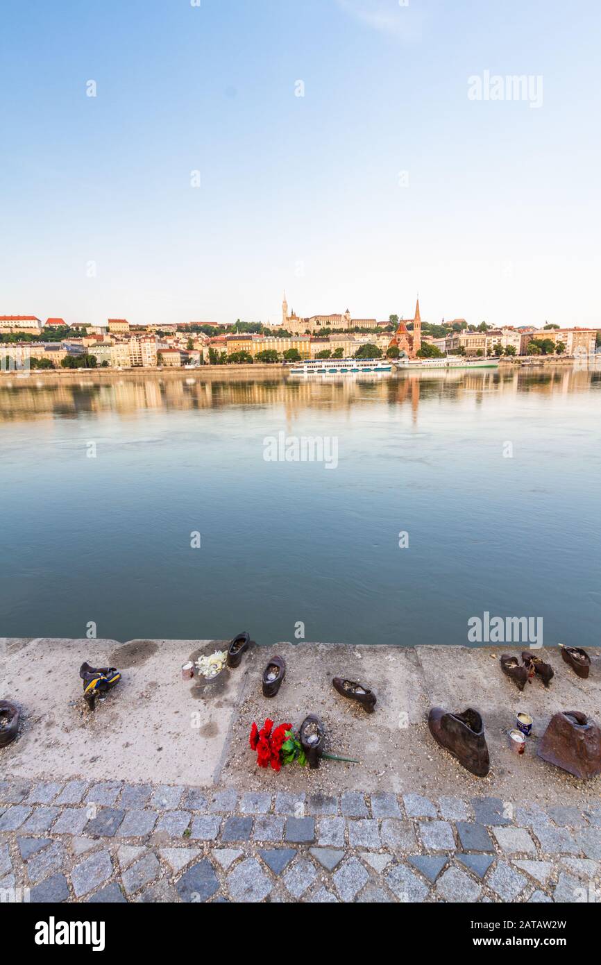 Budapest, Hungary – Shoes on the Danube Bank Holocaust Memorial, portrait just after dawn with river, buildings and their reflections on opposite bank Stock Photo