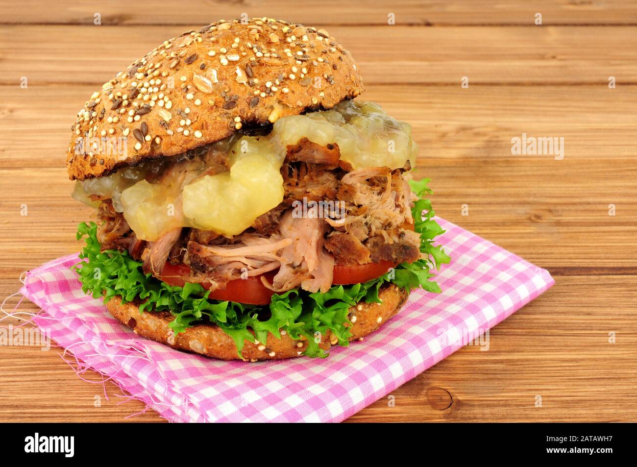 Hog roast meat sandwich with apple sauce and salad in a seed covered bread roll on a wooden background Stock Photo