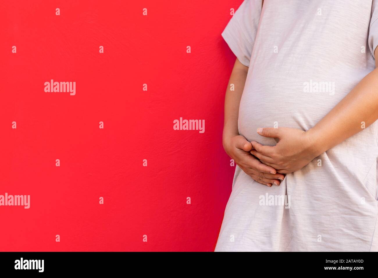 Pregnant woman feeling happy at home while taking care of her child. The young expecting mother holding baby in pregnant belly. Maternity prenatal car Stock Photo