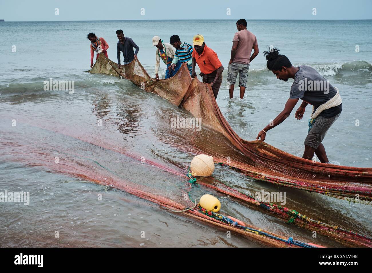 Fishermen pulling the nets out of the ocean on the beach in Sri