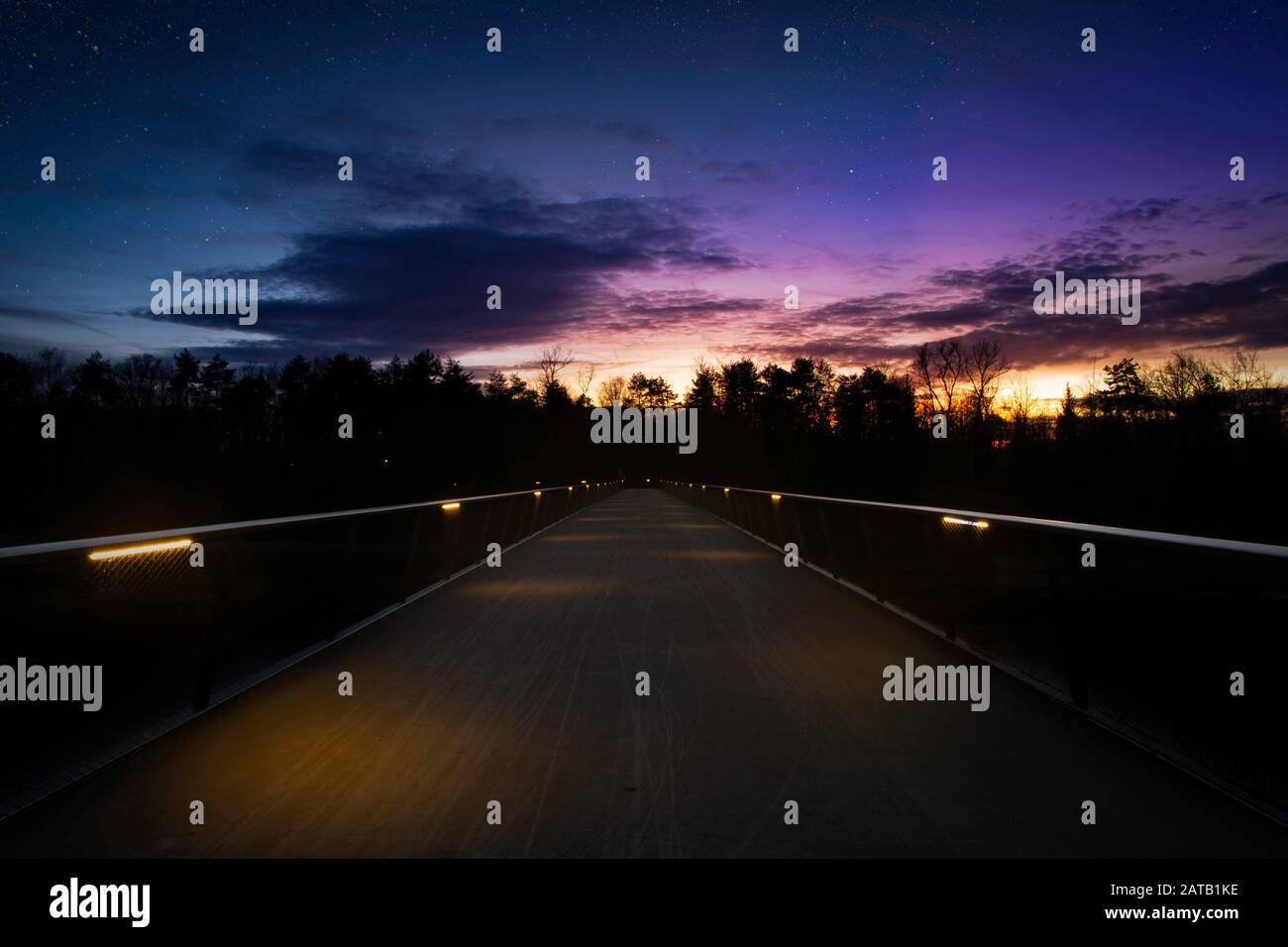 Bicycle bridge at night with starry sky and warm autumn colors Stock Photo