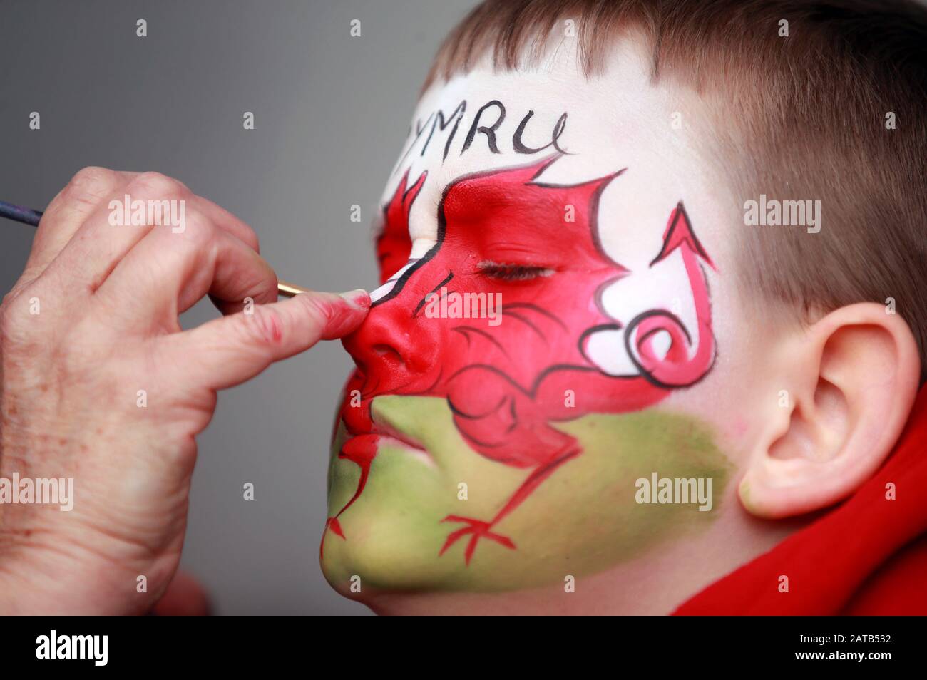 A young Wales fan has his face painted with Y Ddraig Goch (The Red Dragon), the flag of Wales during the Guinness Six Nations match at the Principality Stadium, Cardiff. Stock Photo