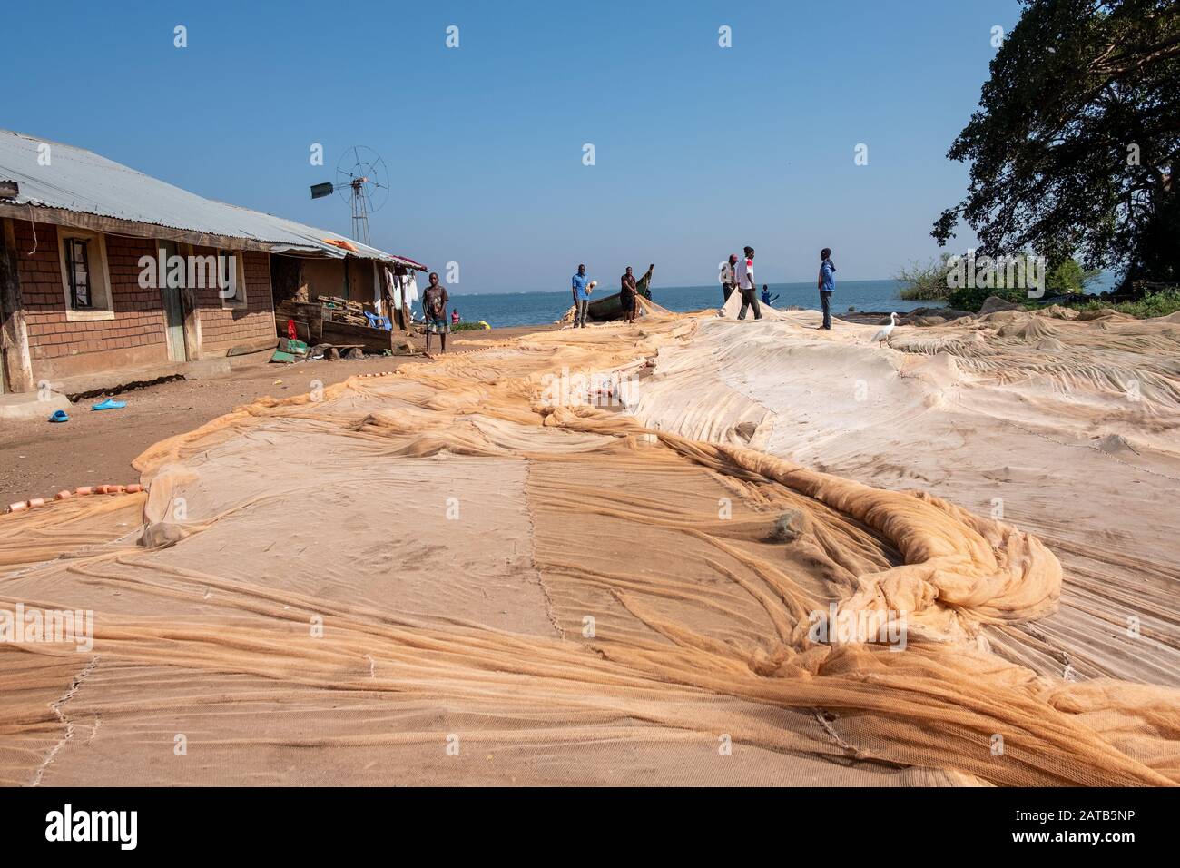 Fisherman stretch out a fishing net to dry in the sun in a Kenyan village on the shores of Lake Victoria, East Africa Stock Photo