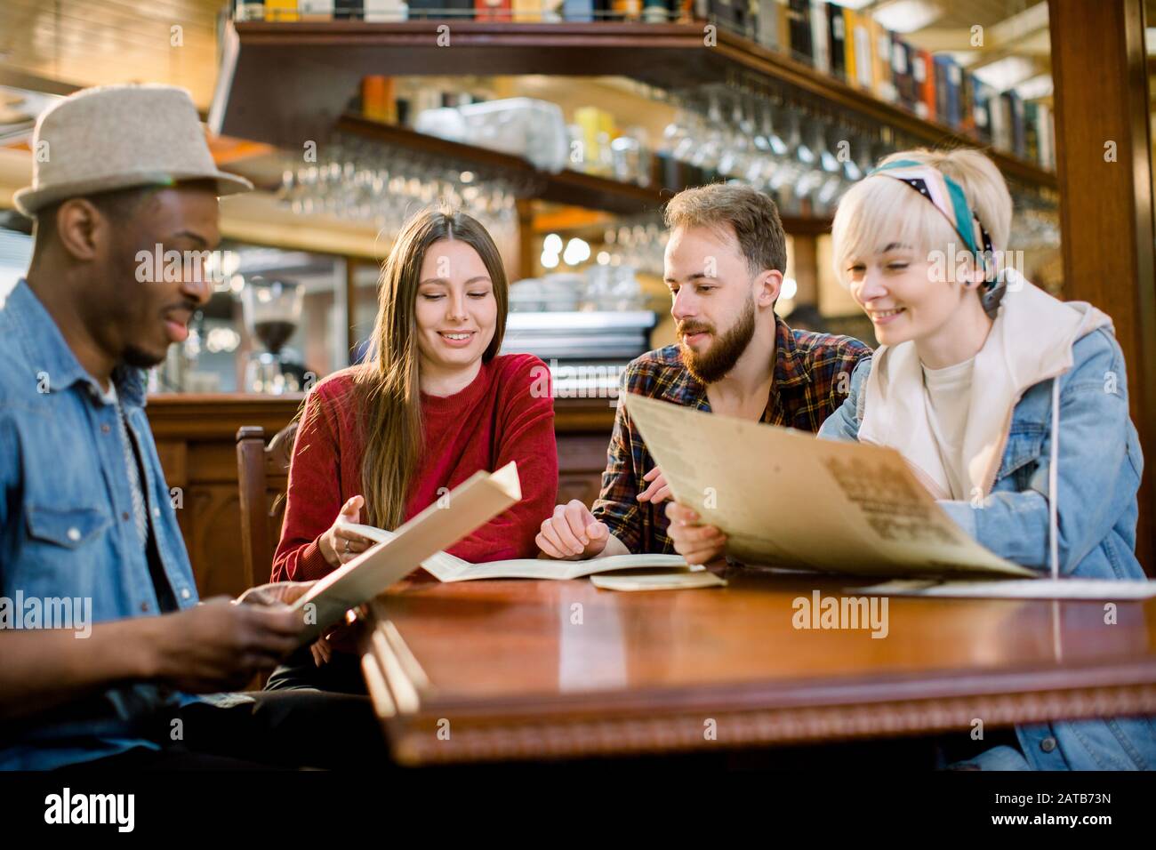 leisure, people and holidays concept - smiling young people in casual  clothes reading menu at restaurant Stock Photo - Alamy