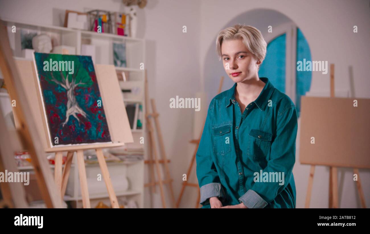 A Young Woman Artist With Short Hair Sitting In The Art Studio