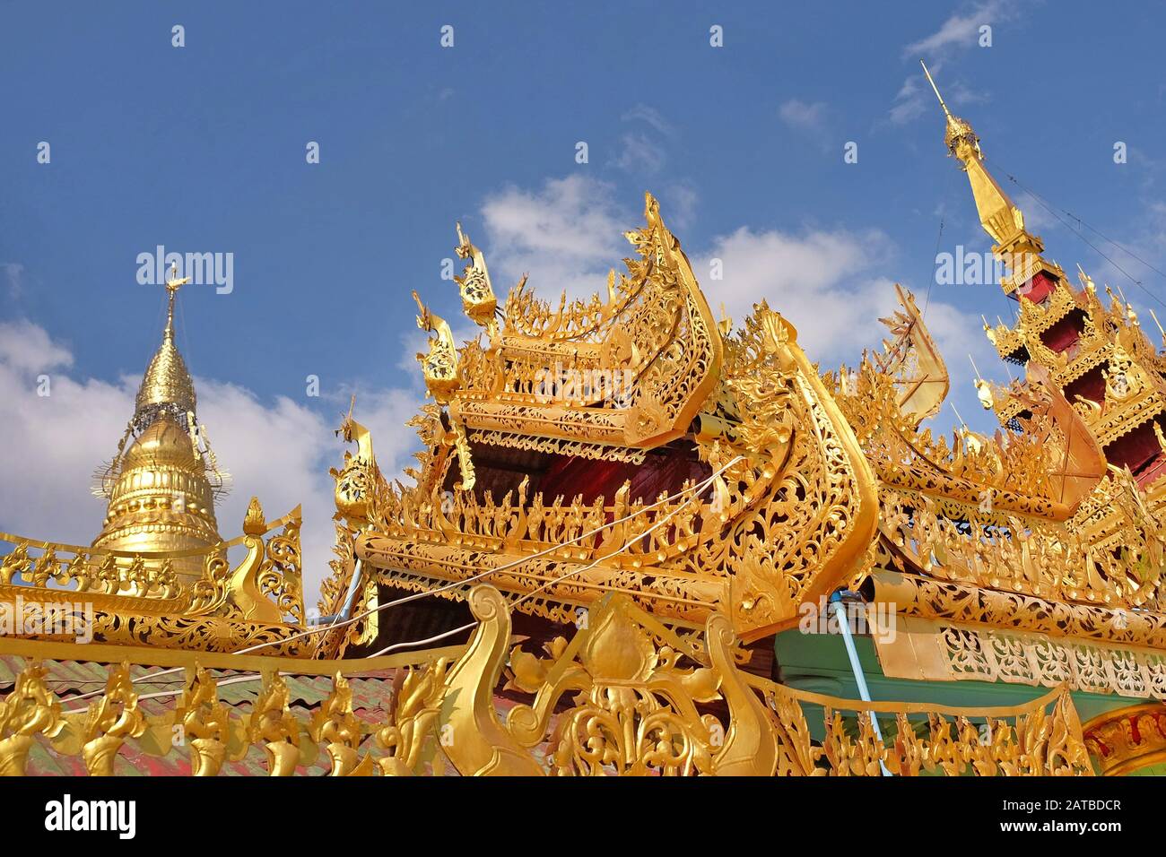 View of the golden roof of a Burmese Pagoda in Mingun, Mandalay, Myanmar, against a blue sky covered by white clouds. Stock Photo