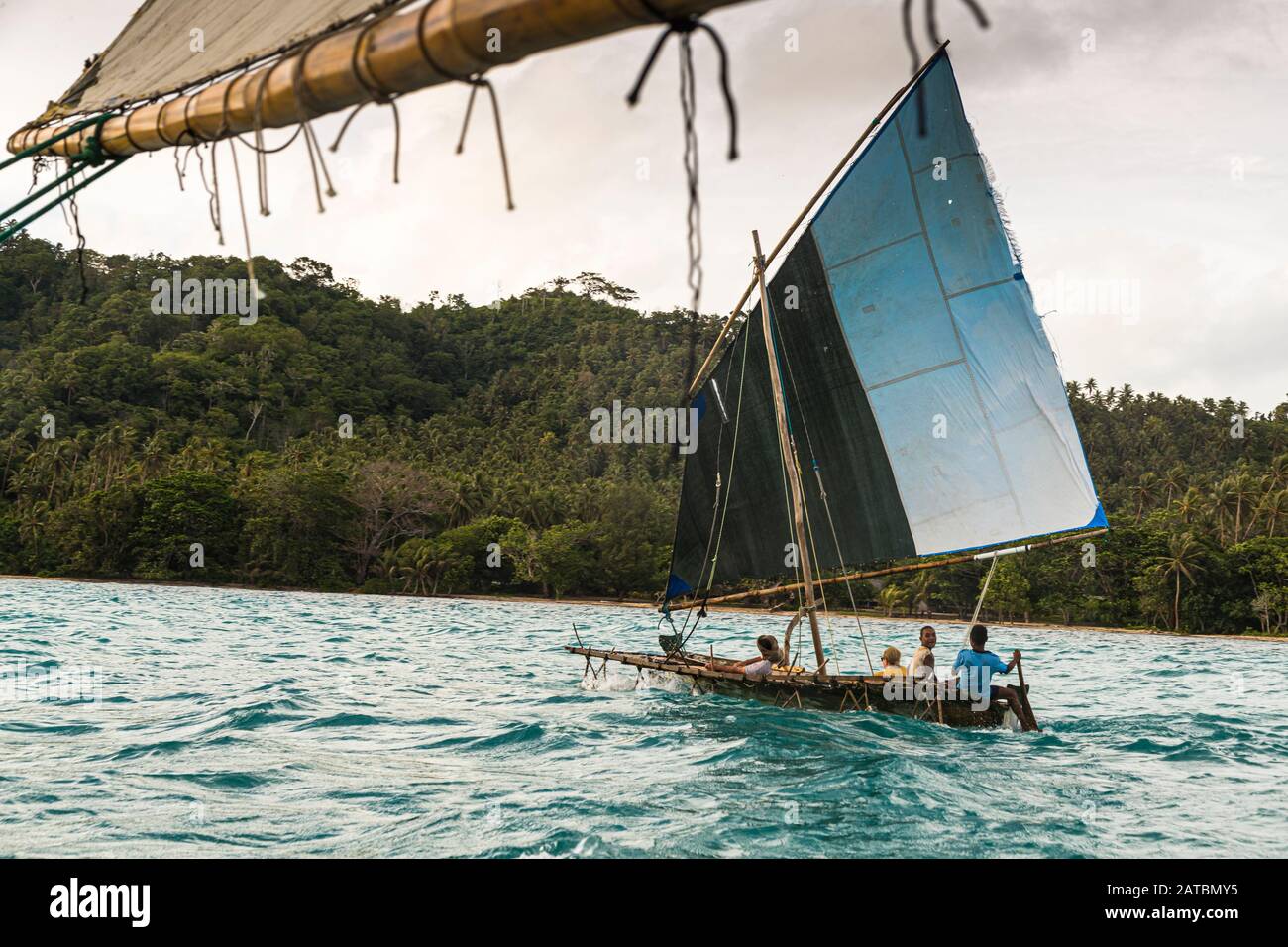 Polynesian style sailing on a Proa (multi-hull outrigger sailboat) in Deboyne Islands, Papua New Guinea. The prau, typical of Polynesia, is an ocean-going sailboat with delta wings and a boom that always lies on the windward side facing the wind Stock Photo