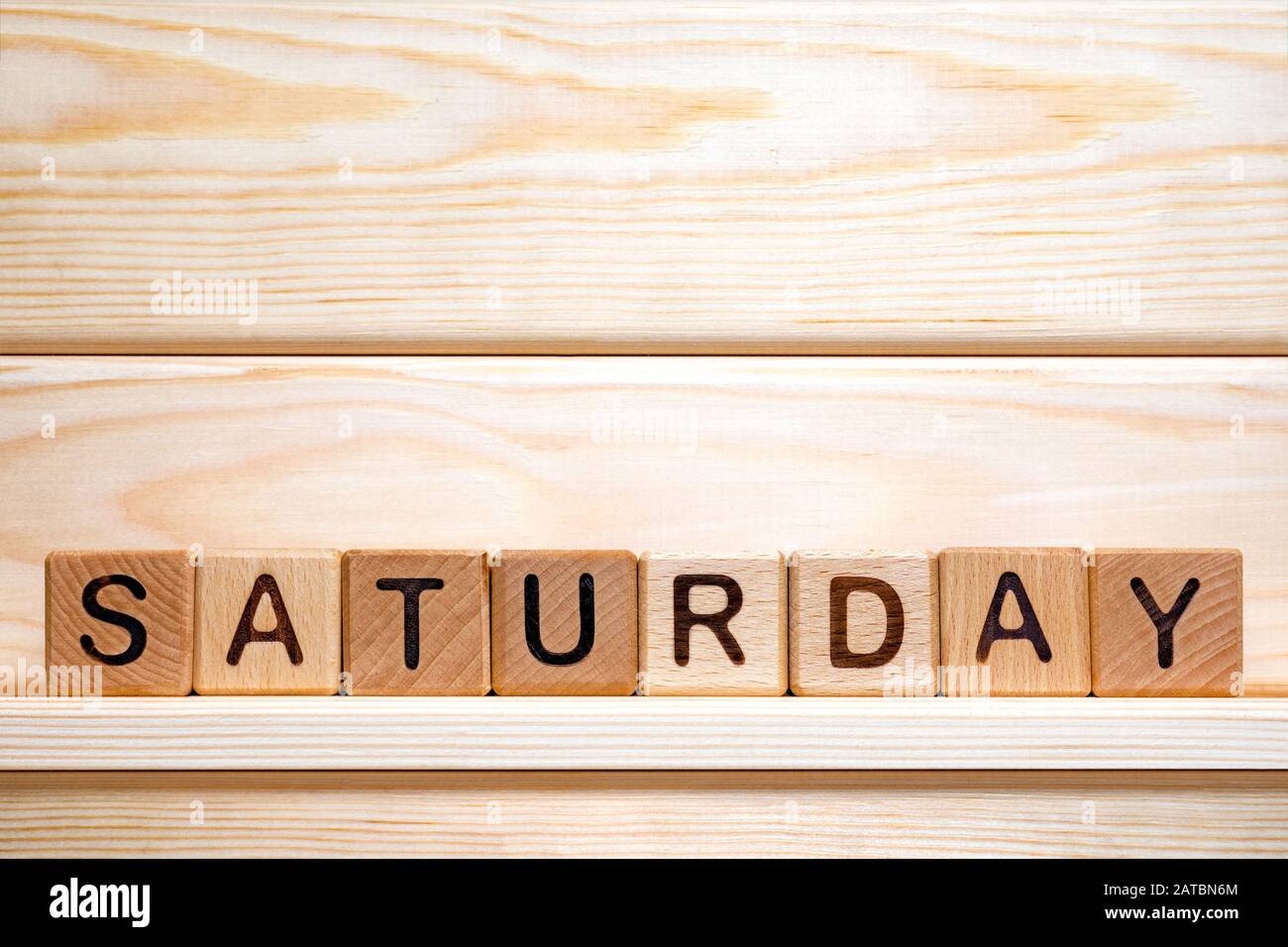 Saturday word written with vintage wooden cubes on wooden background. Day off background. Business concept. Small business. The word Saturday on wooden cubes. Weekday business concept. Stock Photo