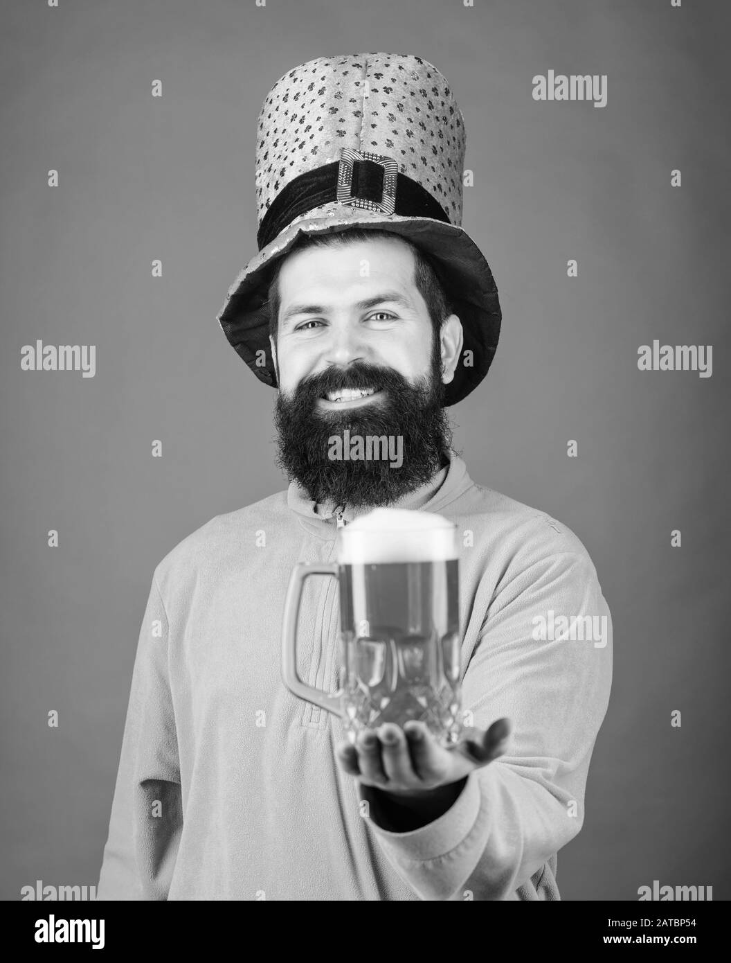 Waiting for you. Bearded man toasting to saint patricks day. Irish man with beard drinking green beer. Celebrating saint patricks day in bar. Hipster in green leprechaun hat holding beer mug. Stock Photo