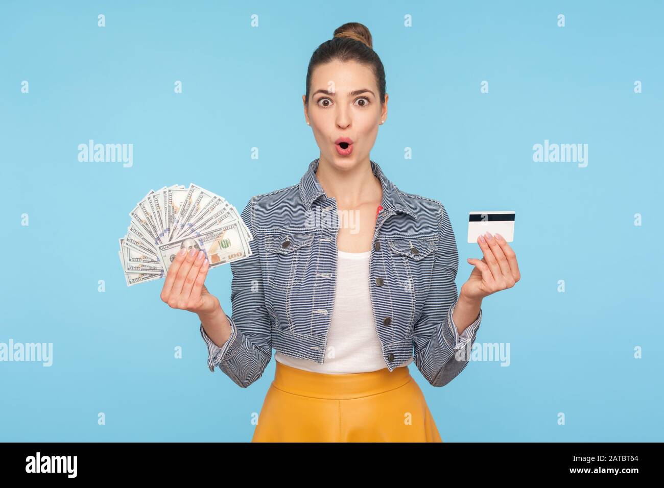 Wow, high-interest loan! Portrait of delighted and surprised woman holding credit card and dollar banknotes, looking with amazement shock at camera. i Stock Photo