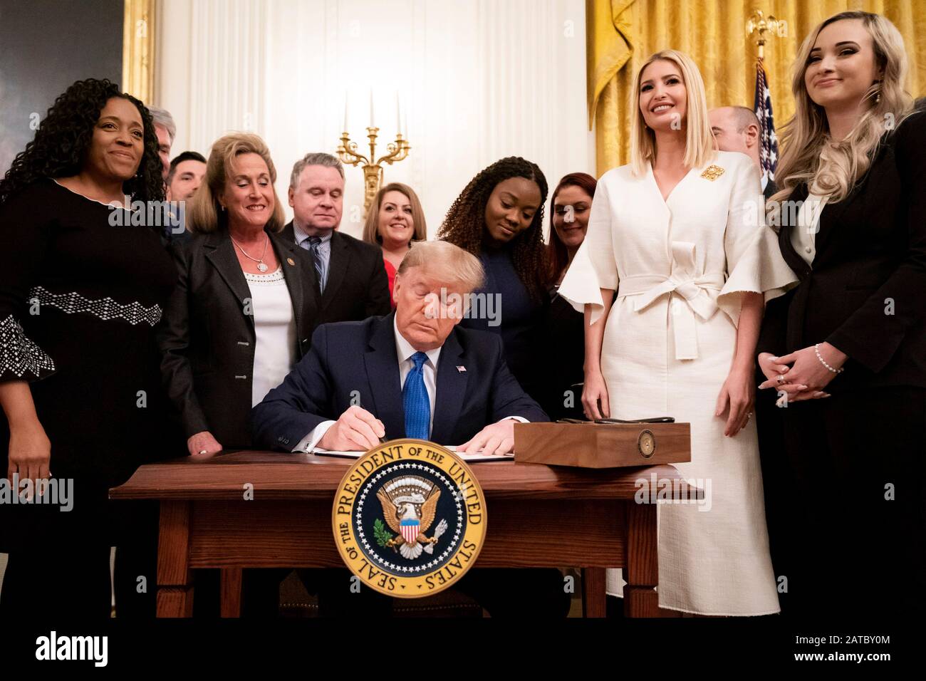 Washington, United States Of America. 31st Jan, 2020. Washington, United States of America. 31 January, 2020. U.S President Donald Trump, surrounded by survivors, officials and his daughter Ivanka Trump, right, signs an executive order to help combat human trafficking during a ceremony in the East Room of the White House January 31, 2020 in Washington, DC. The event took place following the White House Summit on Human Trafficking in honor of the 20th Anniversary of the Trafficking Victims Protection Act. Credit: Tia Dufour/White House Photo/Alamy Live News Stock Photo