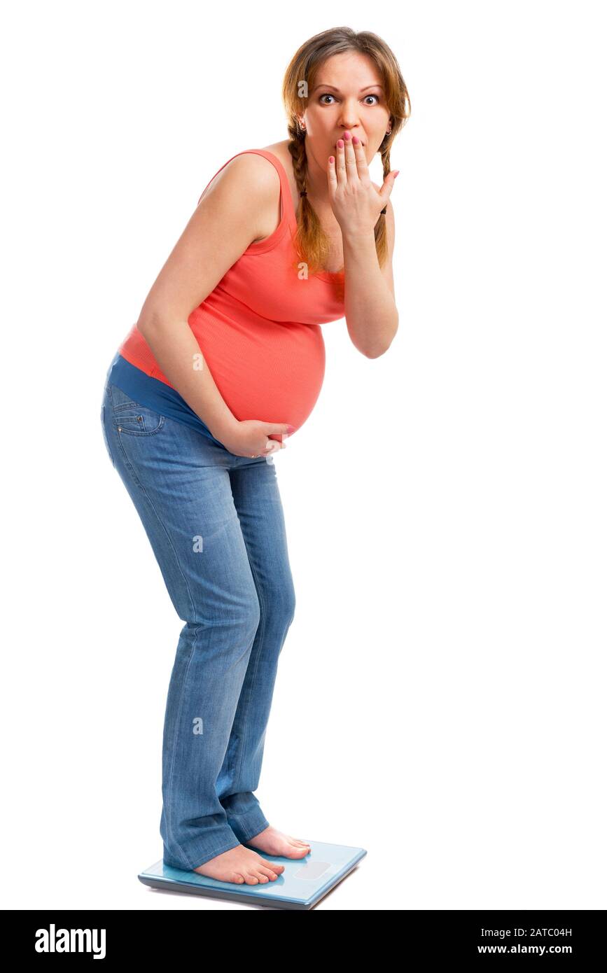 A cute pregnant woman shocked on scale isolated on white Stock Photo