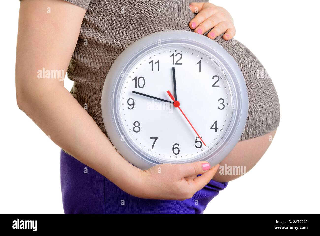 Pregnant woman holding wall clock. It's time. Isolated on white. Stock Photo
