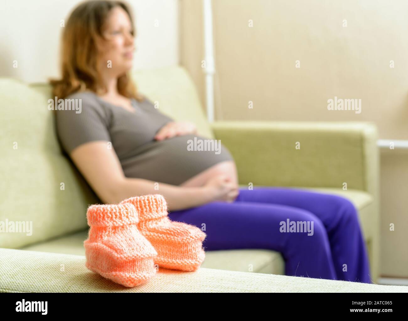 A beautiful woolen booties on the couch next to a pregnant woman Stock Photo