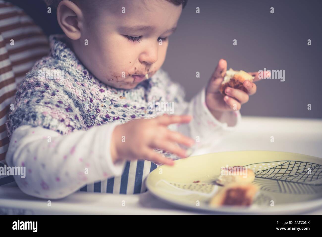 The nice baby with messy face eating cheese cakes Stock Photo