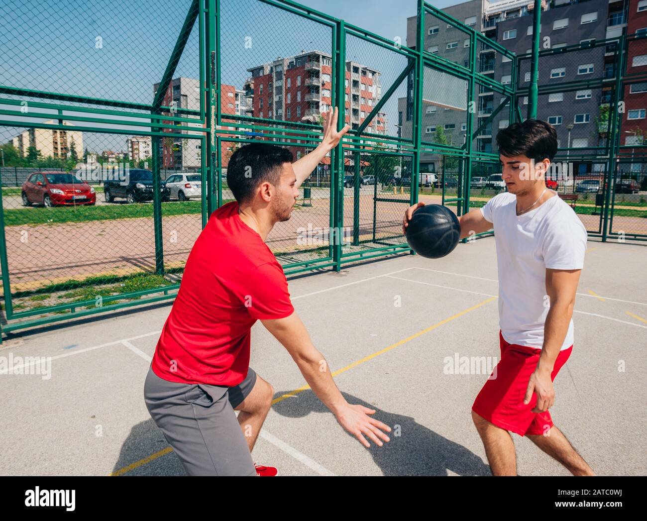Two strong male basketball players play ball out doors fighting for a