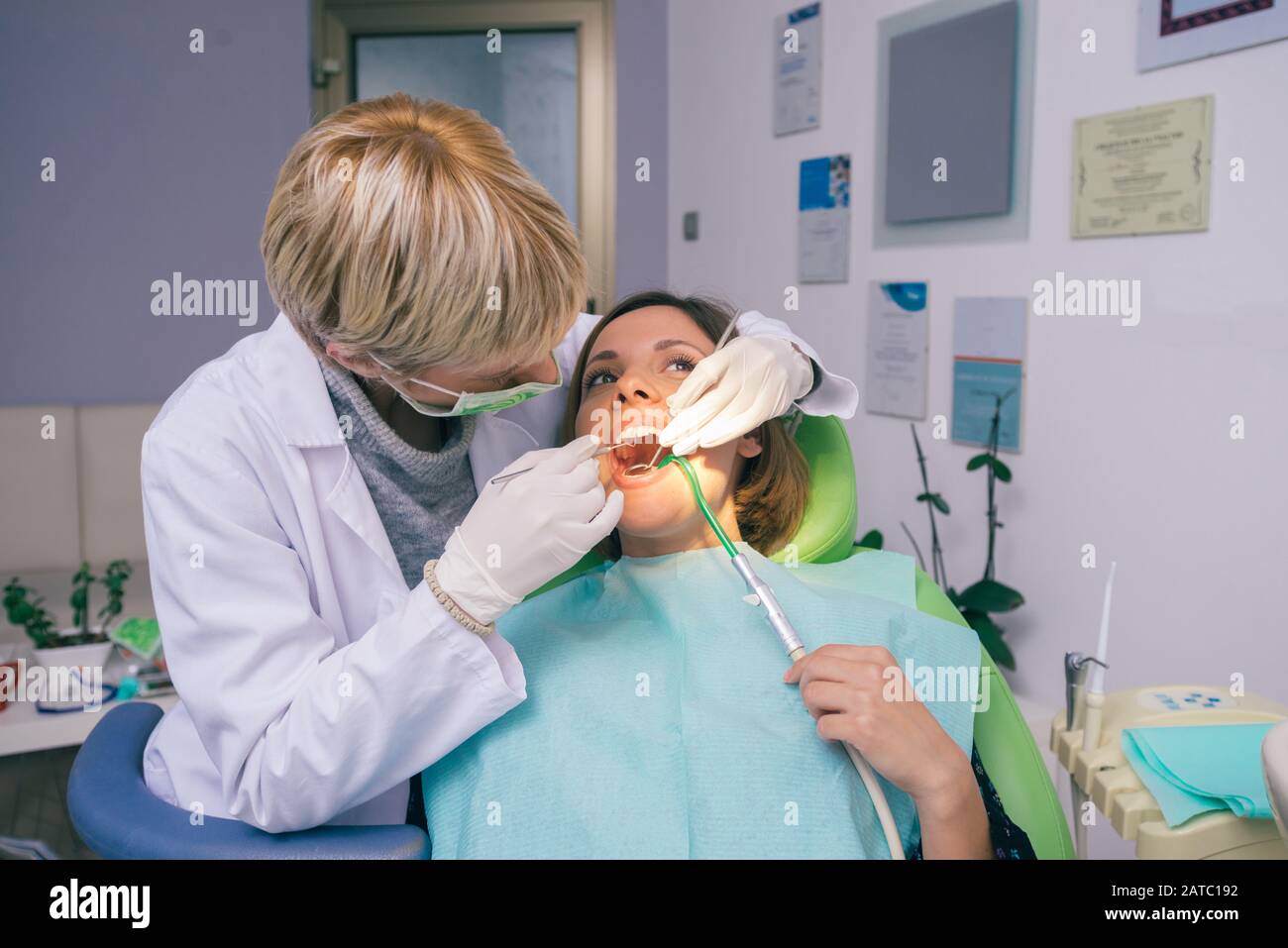 Female dentist in dental office examines the mouth and teeth of a