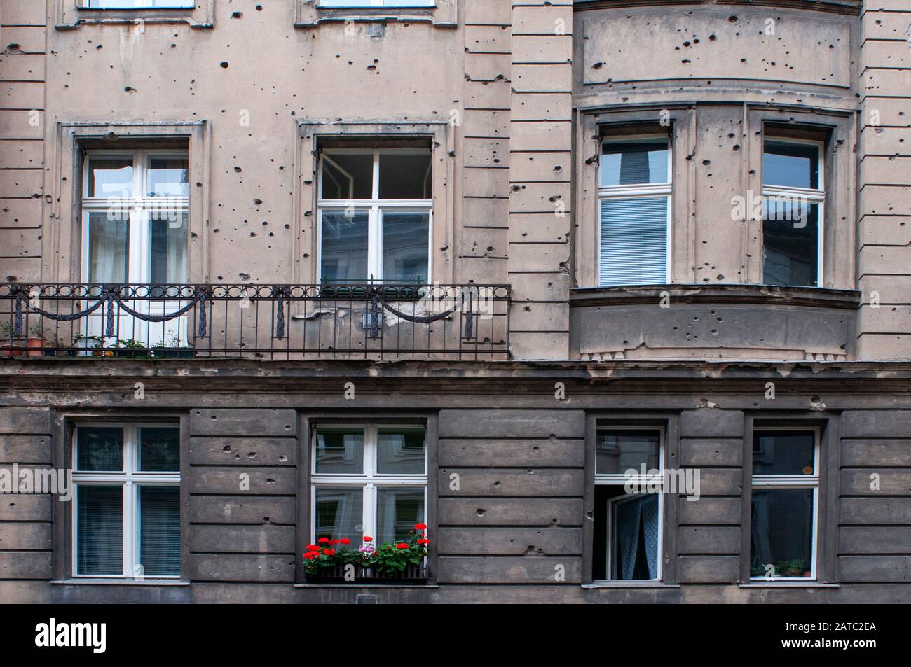 The Scars of the War in Berlin Germany. It seems like a grenade was shot at this house, destroying two windows and their surrounding area. The stones Stock Photo