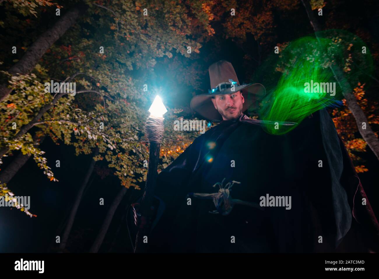 Sorcerer (magician) casting a spell while standing in the magical woods ...