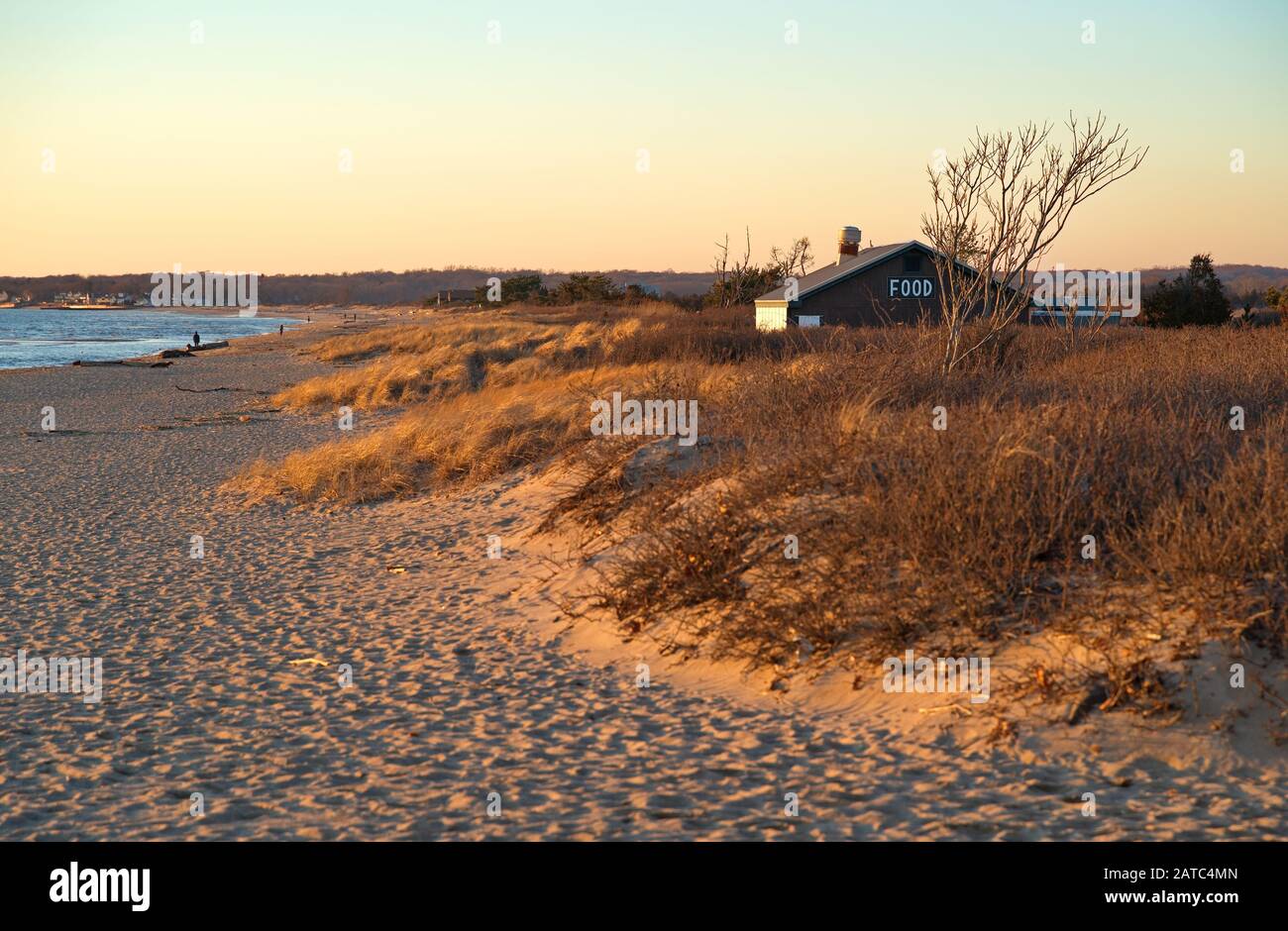 Madison, CT USA. Feb 2019. New England beach restaurant closed during winter season with people in background walking by the chilly afternoon shore. Stock Photo