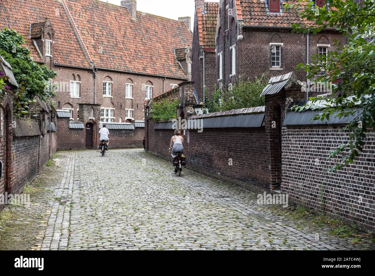 Ghent, Flanders / Belgium - 09 02 2019:Middle aged couple driving the bicycle at the beguinage of Saint Elisabeth and Saint Amandsberg Stock Photo