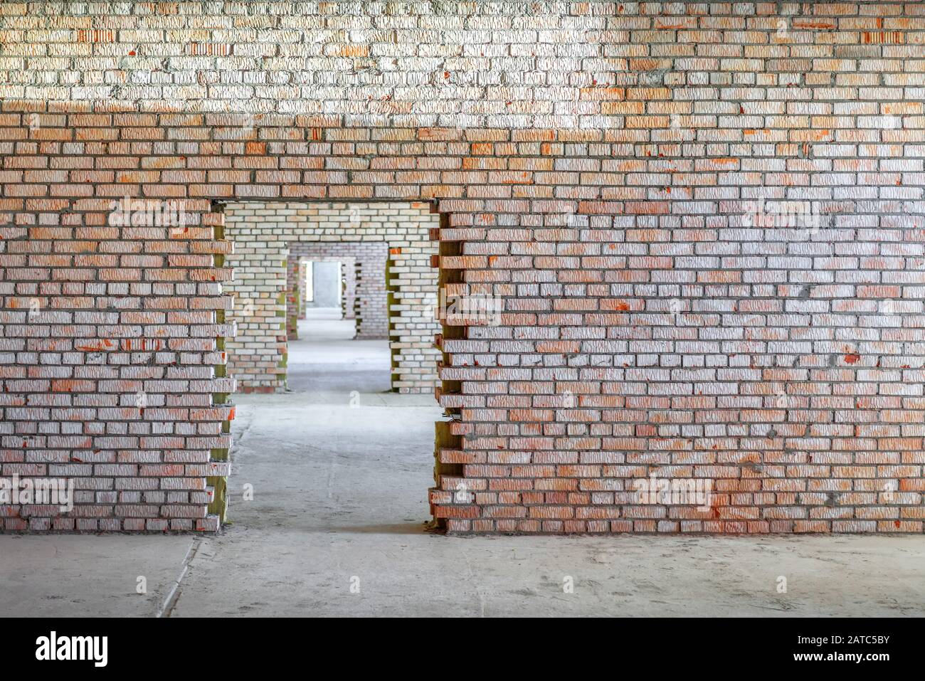 Wall and doorway inside the building under construction. Perspective view of corridor and brick walls for background. Concept of doors and constructio Stock Photo